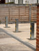 Three Ramco 100 galvanised telescopic security bollards with hi-vis tape installed in a row across a resin-bound driveway entrance