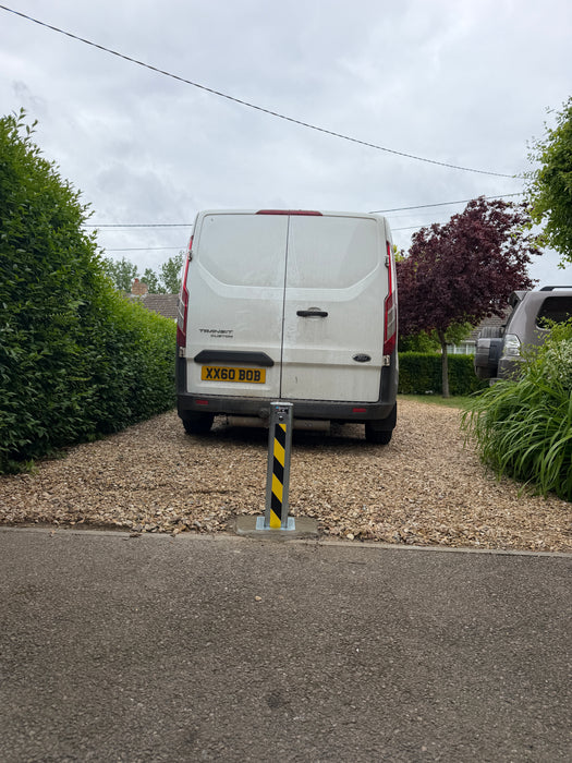Ramco 100 telescopic security bollard with hi-vis tape installed on gravel driveway entrance protecting a Ford Transit Custom van