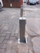 A stainless steel heavy duty security bollard installed by Bison Products on a concrete base with a protective lid and a high security lock.